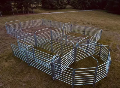 Caperton cattle handling system set up in a field: sweep tub, alley, catch pen and holding pens of galvanized panels