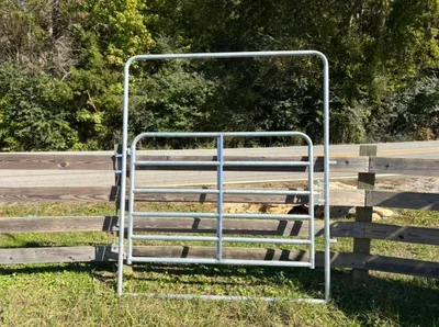 Galvanized 6-foot light bow gate in front of a wood fence