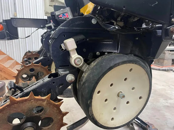 Norseman gauge wheel arm installed on a Kinze planter row unit with a white gauge wheel