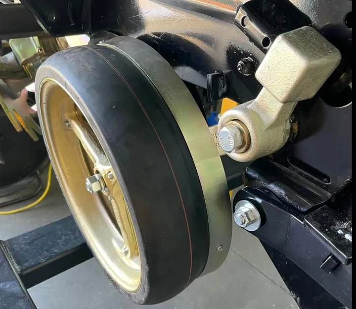 Close-up of a Norseman gauge wheel arm and open spoke gauge wheel on a planter row unit