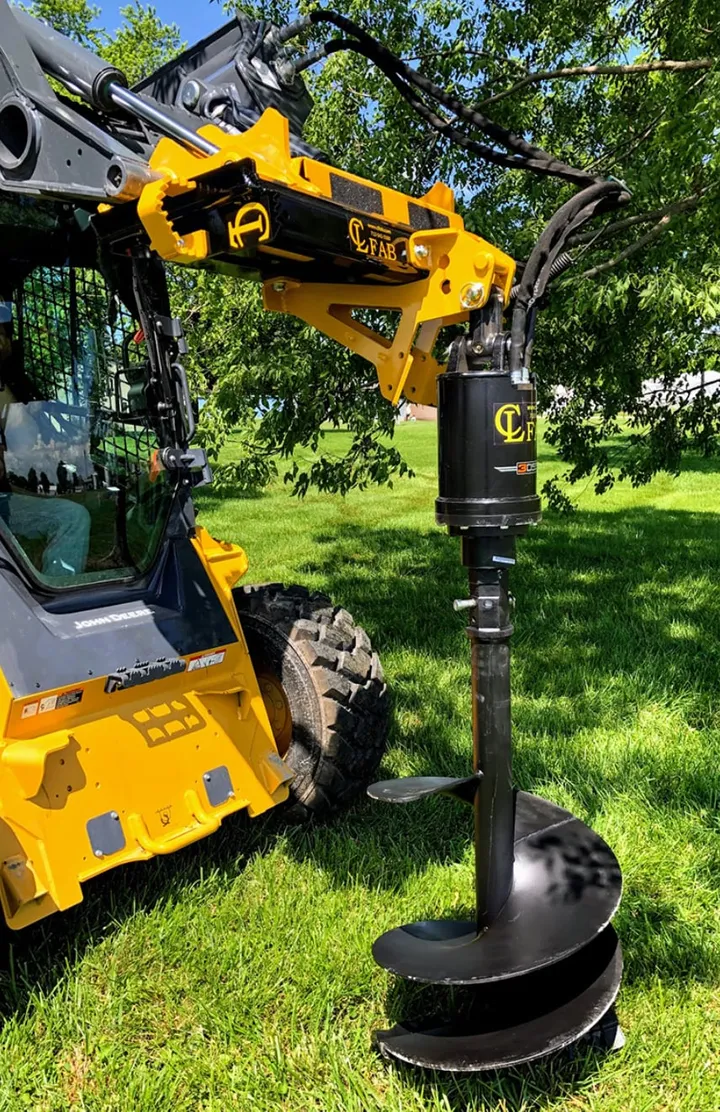 Auger drive on a skid steer with the auger raised, under trees